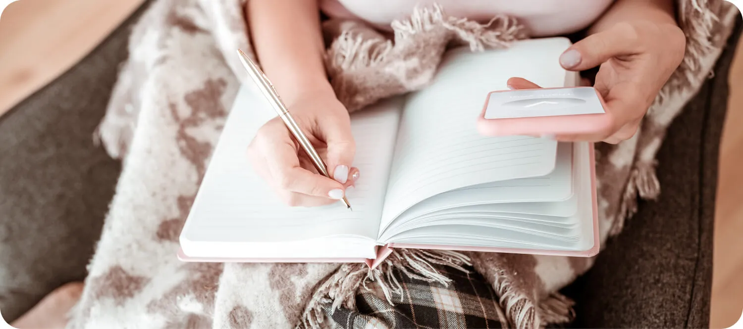 Hand writing in an open notebook on a blanket