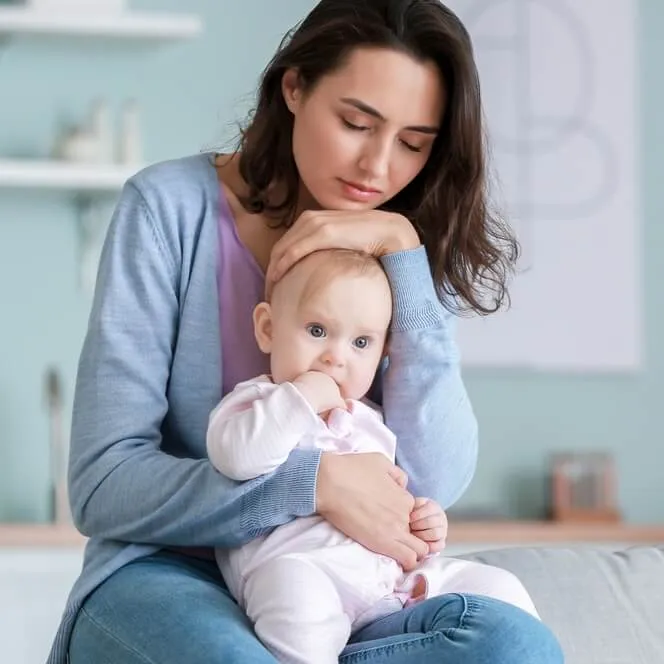 Mother with her eyes closed holding her baby close against her cheek