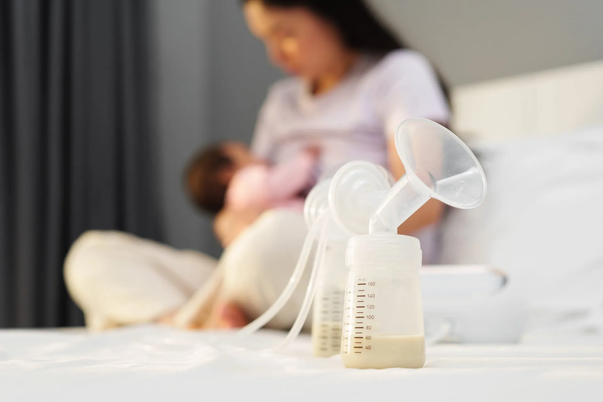 Mother holding a bottle of pumped breast milk with measurement marks