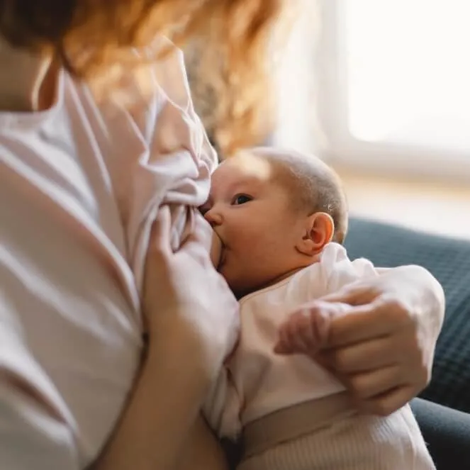 Mother breastfeeding her baby in soft window light
