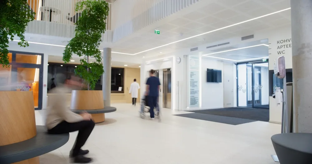 Bright hospital lobby with a nurse pushing a wheelchair down the hall