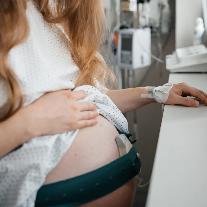 Pregnant woman in a hospital gown wearing a contraction monitor belt